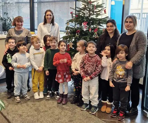 Kitas schmücken Weihnachtsbaum und freuen sich mit Geschäftsführerin Maria Creeten über den schönen selbstgebastelten Schmuck